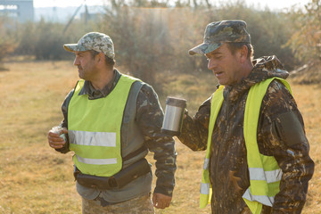 Hunter with a german drathaar and spaniel, pigeon hunting with dogs in reflective vests	