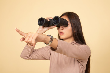 Young Asian woman  point and look with binoculars.