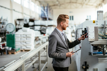 Manager checks machines at the factory.  Inspector checks a factory.  Supervisor runs his daily check at work. Factory worker setting the tech up for work.