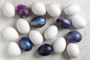 Easter eggs with cosmic pattern and white Easter eggs on the marble surface