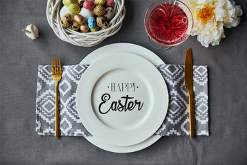 top view of festive table setting for Easter with decor, painted eggs and happy Easter lettering on plate