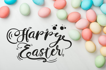 top view of multicolored chicken painted eggs on grey background with happy Easter black lettering