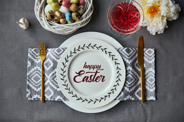 top view of festive table setting for Easter with decor and happy Easter lettering on plate