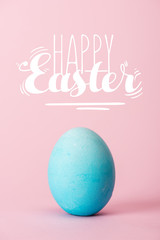 blue chicken egg on pink background with happy Easter lettering