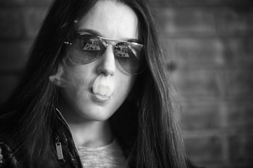 Vape teenager with  problem skin. Portrait of young cute girl in sunglasses smoking an electronic...