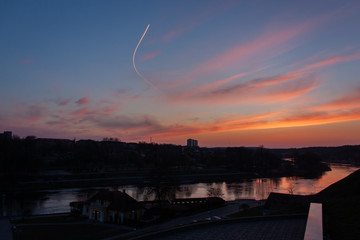 Landmarks and views of Grodno, Belarus. A bright and beautiful sky with a trace of the overflying aircraft, and the Neman River, with a pink reflection of the sky, after sunset.
