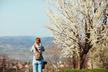Girl photographer enjoying spring day in nature with a blooming cherry tree.