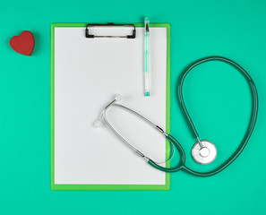 empty white sheets and a medical stethoscope on a green background