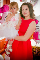 A little fair-haired girl, a child with blue eyes, dressed in a pastel pink dress, celebrates her birthday  