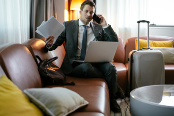 Manager on his phone, at a hotel room. Businessman gets ready for the meeting.