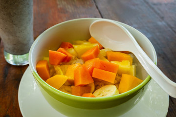 Mixed fruit salad in the bowl on wooden background