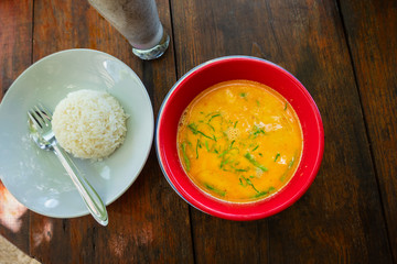 Thai yellow curry soup with rice on rustic table