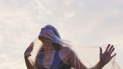 Portrait Of A Young Woman Entangled In Plastic Foil, Breaking Free.