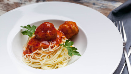 Close-Up spaghetti and meatballs in tomato sauce on a white plate