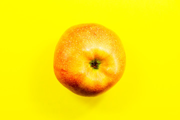 Red ripe apple on a yellow background. View from above.