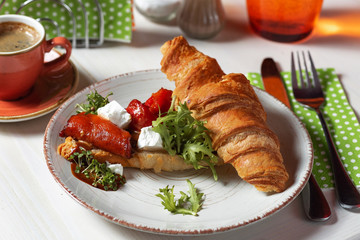 Croissant with arugula and cheese on a white plate