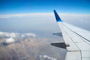 Obraz premium View from a landing airplane out the window travel. Wing of an airplane flying above the clouds over tropical island Turkey. Wing of airplane flying above the clouds in the sky