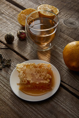 glass of traditional chinese blooming tea, lemons and honeycomb on wooden surface