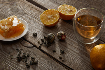 glass of chinese blooming tea, lemons and honeycomb on wooden table