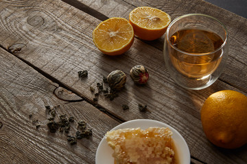 glass of traditional chinese blooming tea, lemons and honeycomb on wooden table