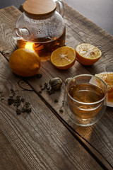 lemons, tea balls and transparent teapot with glass of traditional chinese blooming tea on wooden surface