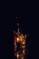 shot of whiskey with splash on black background