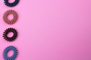 Plastic spiral scrunchies hair band for women hairdressing hairstyle on pink background with free copy space for text flat lay