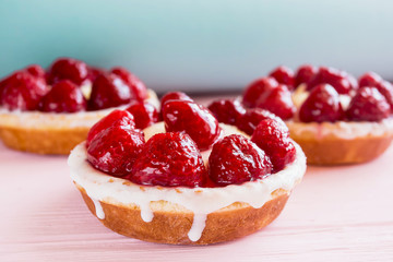 three panna cotta cakes with cream and raspberries close up on a gentle blue sky and pink background