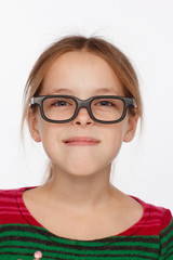 Fototapeta premium Portrait of 8-year-old girl in glasses and a sweater in a crimson and green stripes. Studio photo session