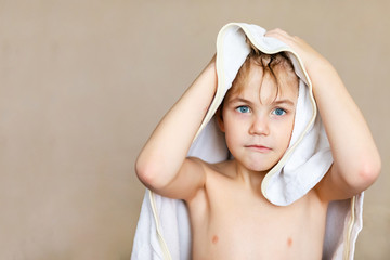 Blode caucasian boy after bath with wet hair and white towel on the head. Funny face, great smile,...