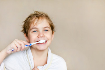 A cute little blonde boy with blue eyes brushing his teeth with a toothbrush. The concept of children's health, medicine