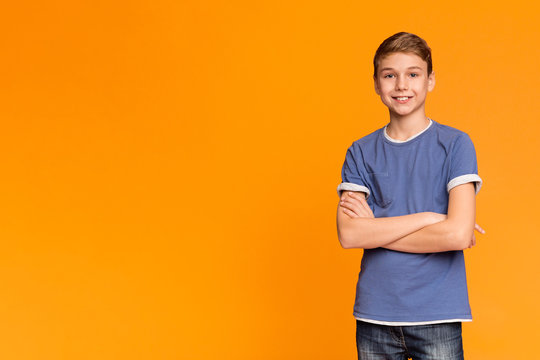 Cute teenage boy posing with folded hands and smiling