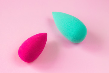 Beauty blender for cosmetics in the hand on pink background
