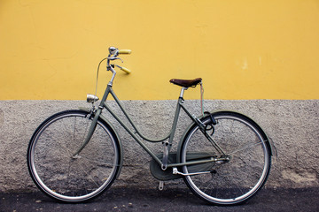 Stylish retro vintage bike against the background of a colored gray and orange halfside wall in Bergamo lower side of town.