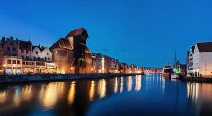 Obraz premium Old town in Gdansk, Poland at night. Riverside with the famous Crane and city reflections in the Motlava river. High resolution panorama.