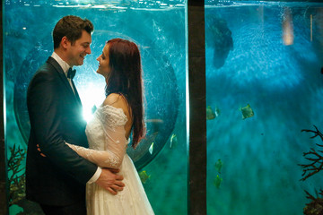 Happy wedding couple posing in front of aquarium