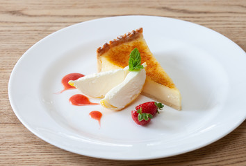A sweet dessert tart served with ice cream, fruit coulis and fresh strawberries served on a white plate in a restaurant