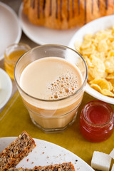 Mug of coffee on the table with English breakfast and croissant