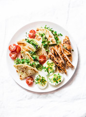 Grilled chicken, avocado cream cheese quesadilla, boiled eggs, vegetables - delicious snack, appetizer, tapas on a light background, top view