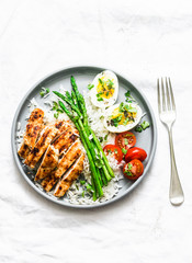 Balanced healthy lunch - rice, asparagus, grilled chicken, boiled egg on a light background, top view