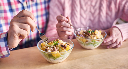 Male sitting next to female and having light fruit mix salad for breakfast. Focus on bowl with dessert useful dish. Concept of family healthy lifestyle and nutrition. Cropped view. Blurred background.