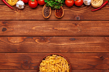 Pasta and ingredients on wooden background with copy space. Top view.