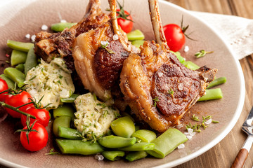 Grilled lamb chops with a garnish of green beans and fragrant butter. With tomatoes and fresh thyme. Homemade cooked dish. Ketogenic food.  Close up horizontal view.
