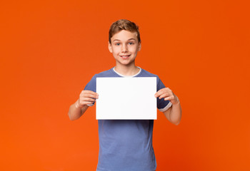 Cute smiling boy holding white blank placard