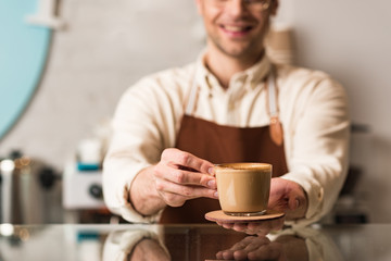 Selective focus of barista holding cup of coffee