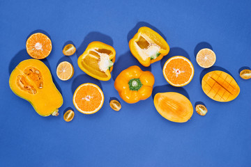 Collection of fresh yellow fruit and vegetables on the blue background