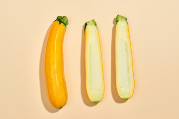 Whole and half of a zucchini isolated on pastel background.