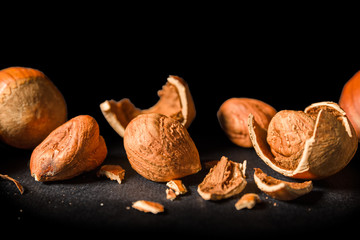Some shelled hazelnuts with shell fragments around them, isolated on a black background