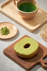 Green tea matcha in a wooden cup with German cake on the brown mat close-up