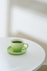 Matcha tea in a green cup on the white table, top view